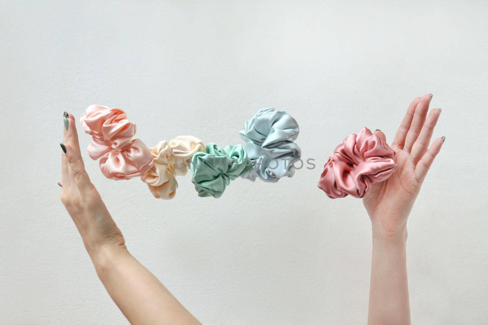 Lot of floating Colorful silk Scrunchies on womas hands isolated white. Hairdressing tools and accessories. Hair Scrunchies, Elastic HairBands, flying or falling Scrunchie Hairband for girls or ladies