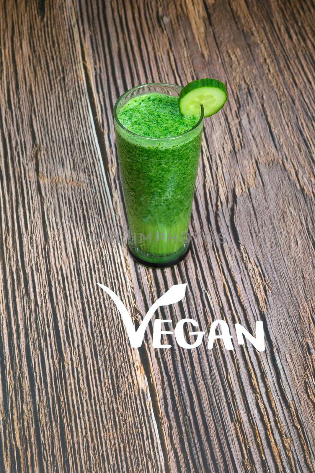 Healthy fresh green shake or smoothie with green vegetables spinach, avocado, apple on wooden background texture with the text Vegan top view, copy space freshness