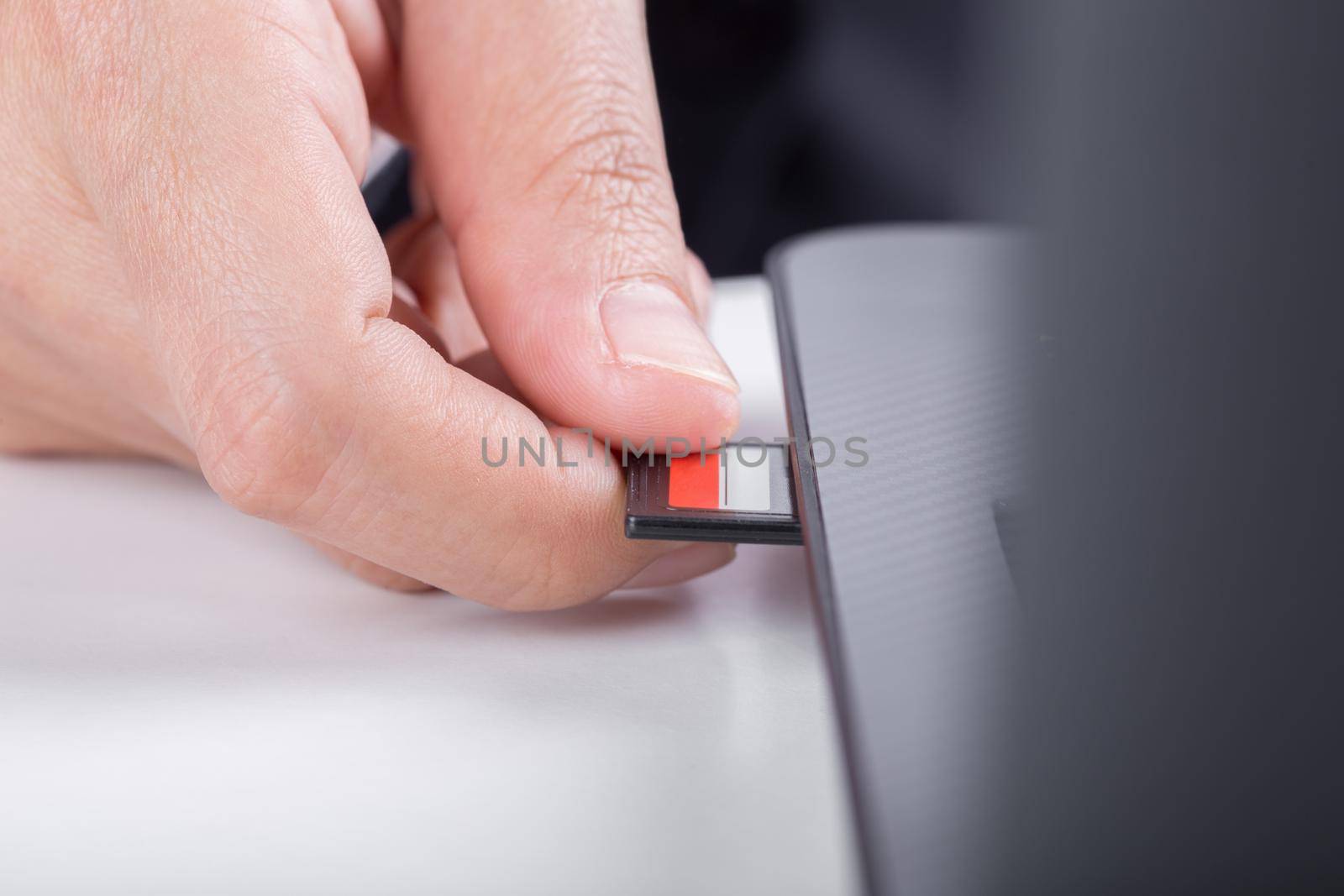  hand inserting SD card into laptop slot