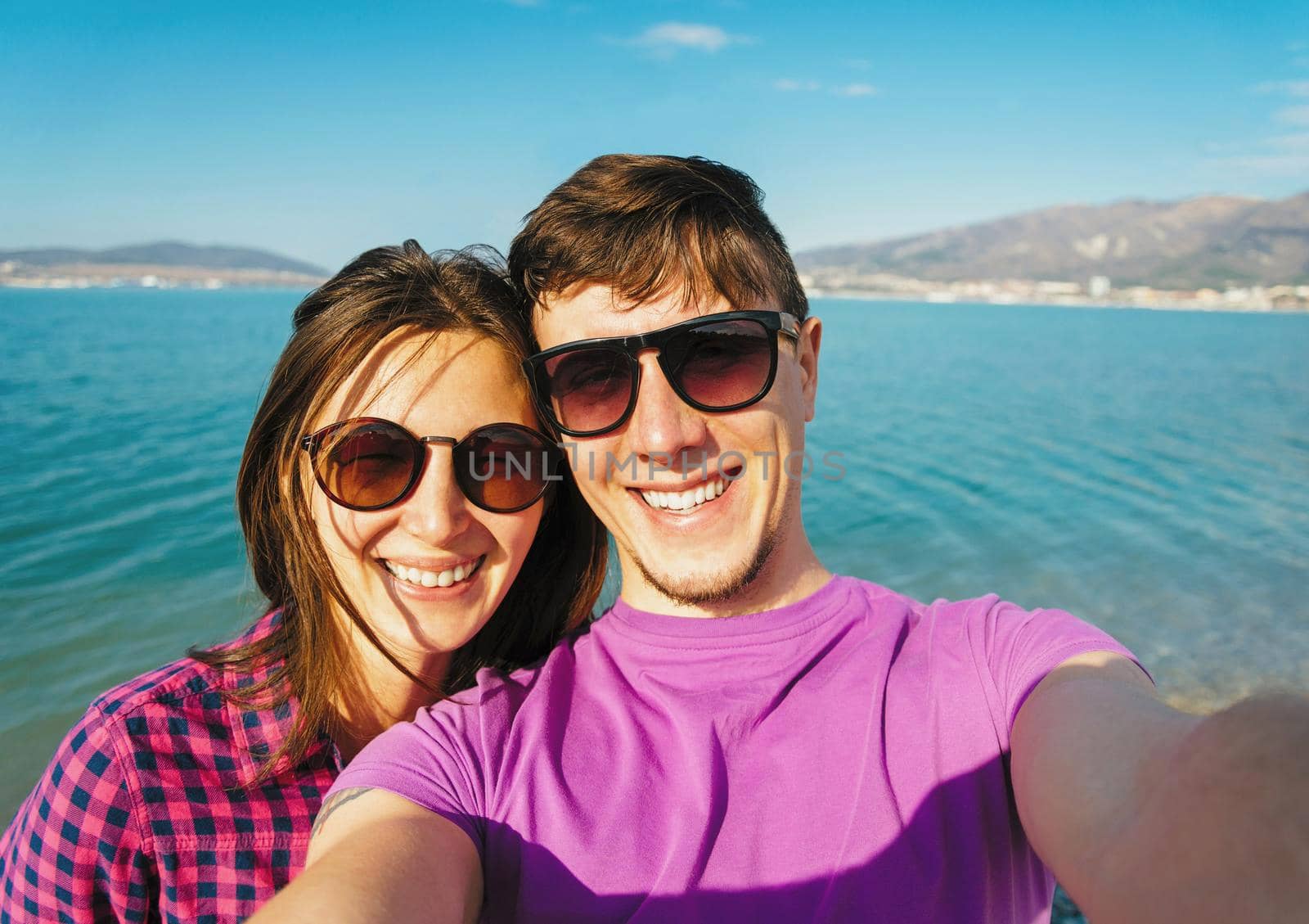 Happy young couple in love taking self-portrait on background of blue sea