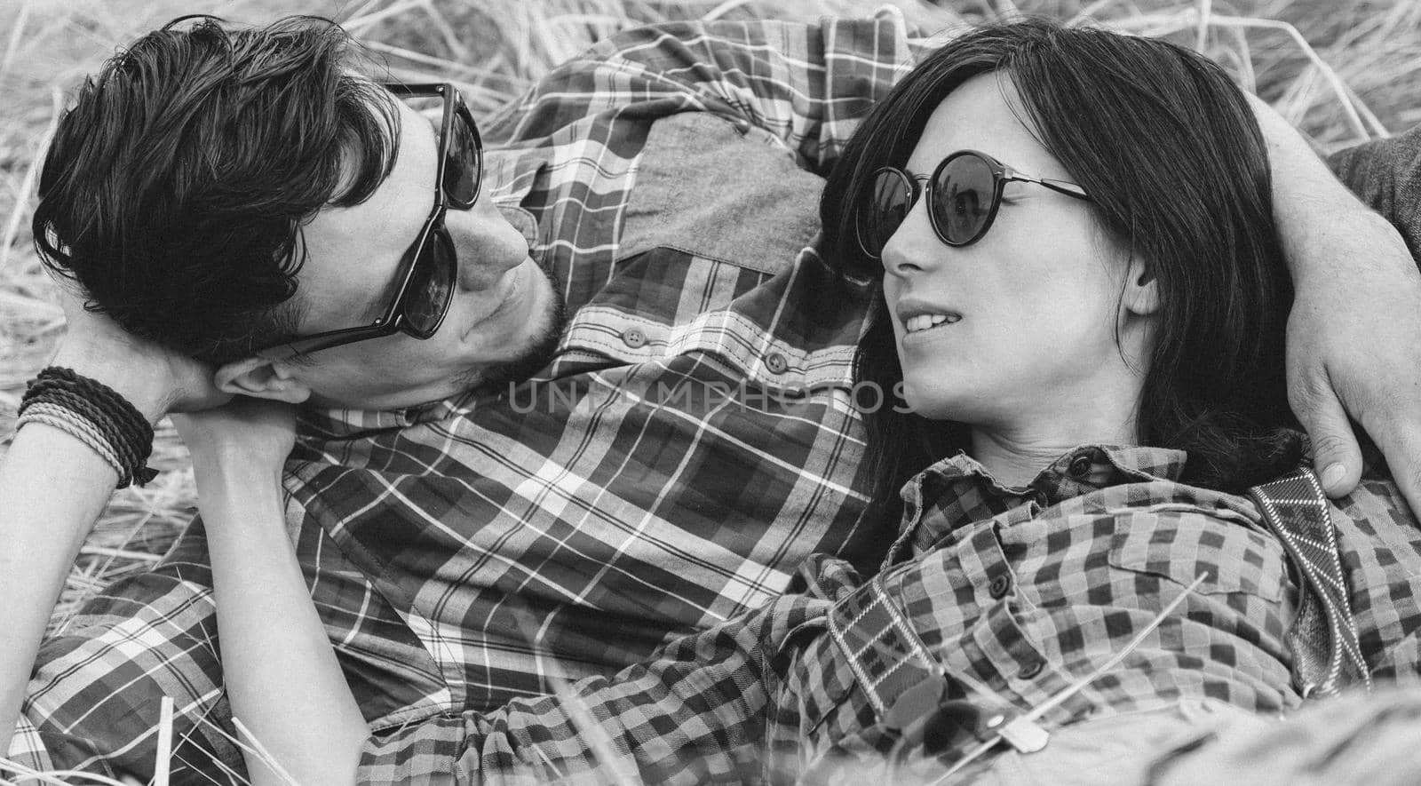 Young hipster style couple is talking to each other outdoor. With film grain effect. Black-white photo.