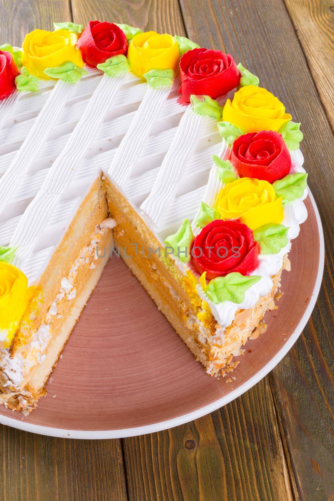 Cut biscuit cake on plate on wooden table close up