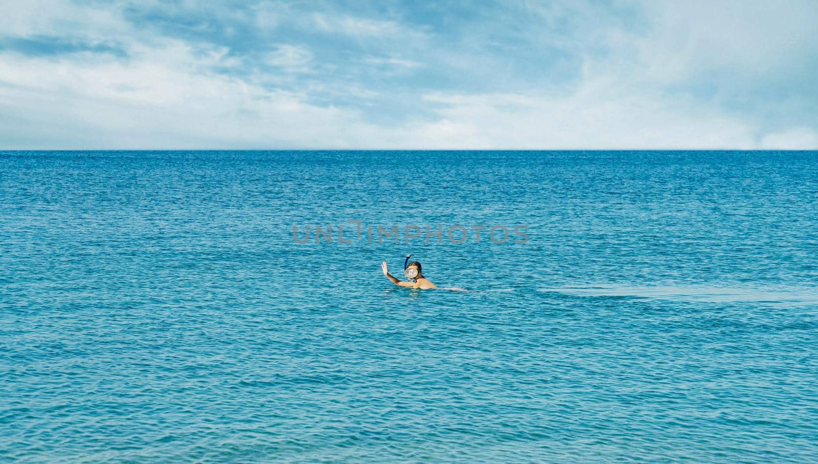 Happy young woman snorkeling in mask in the tropical blue sea