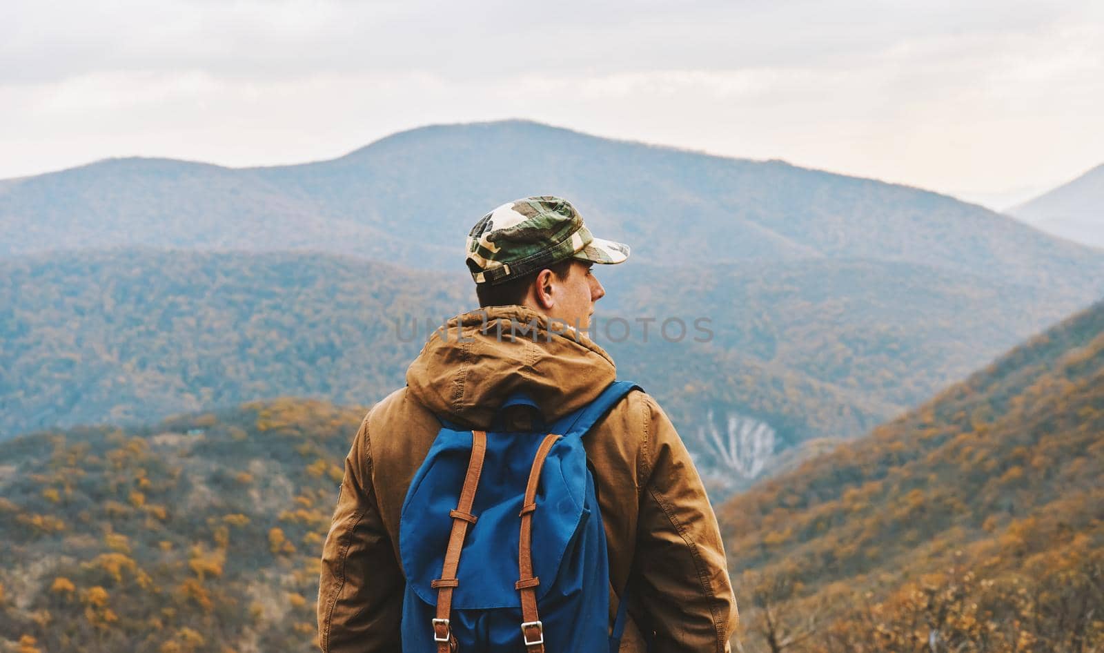 Hiker man with backpack standing among mountains and enjoying by scenics in autumn season
