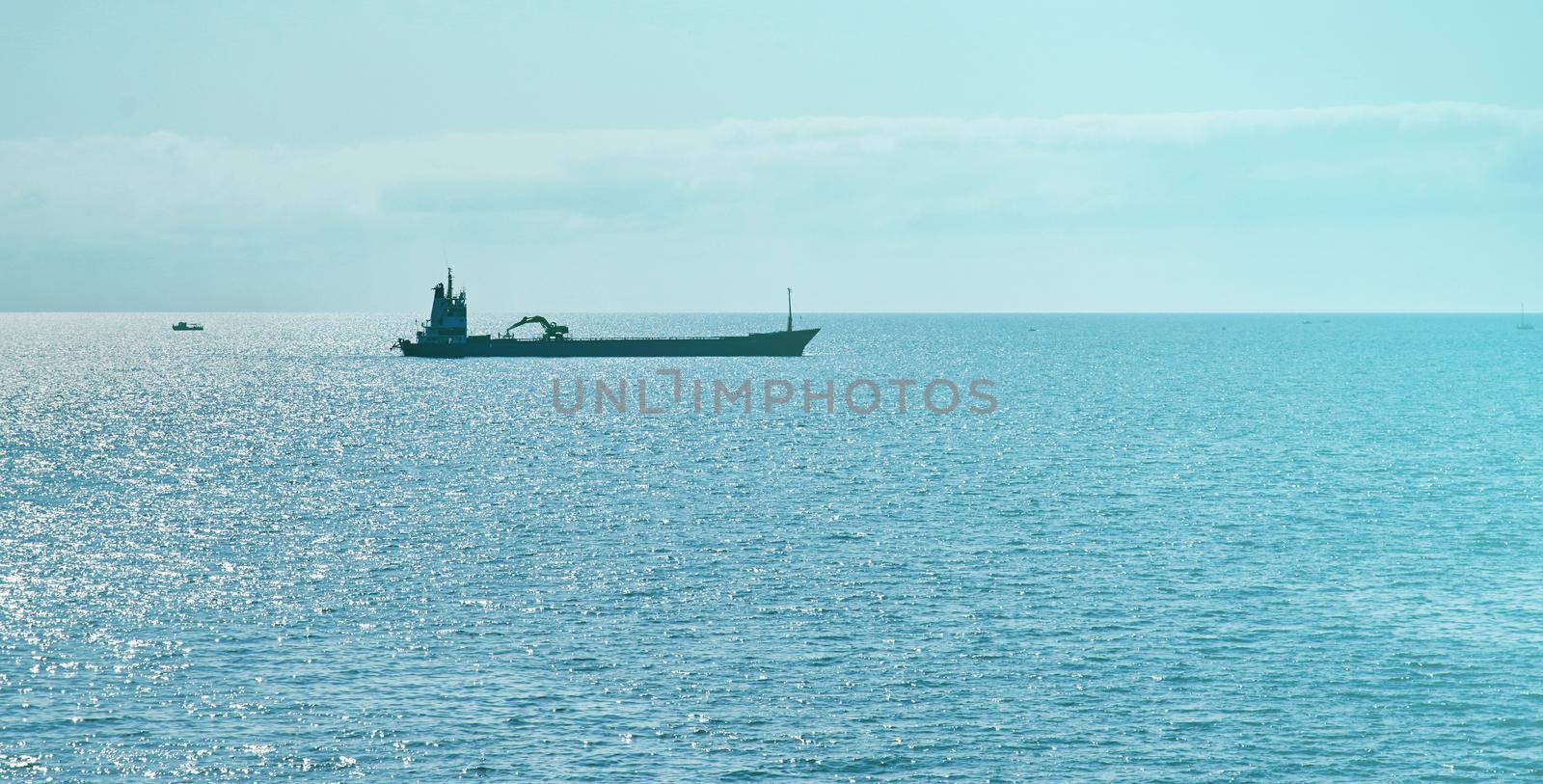 Cargo ship in the blue ocean at sunny day