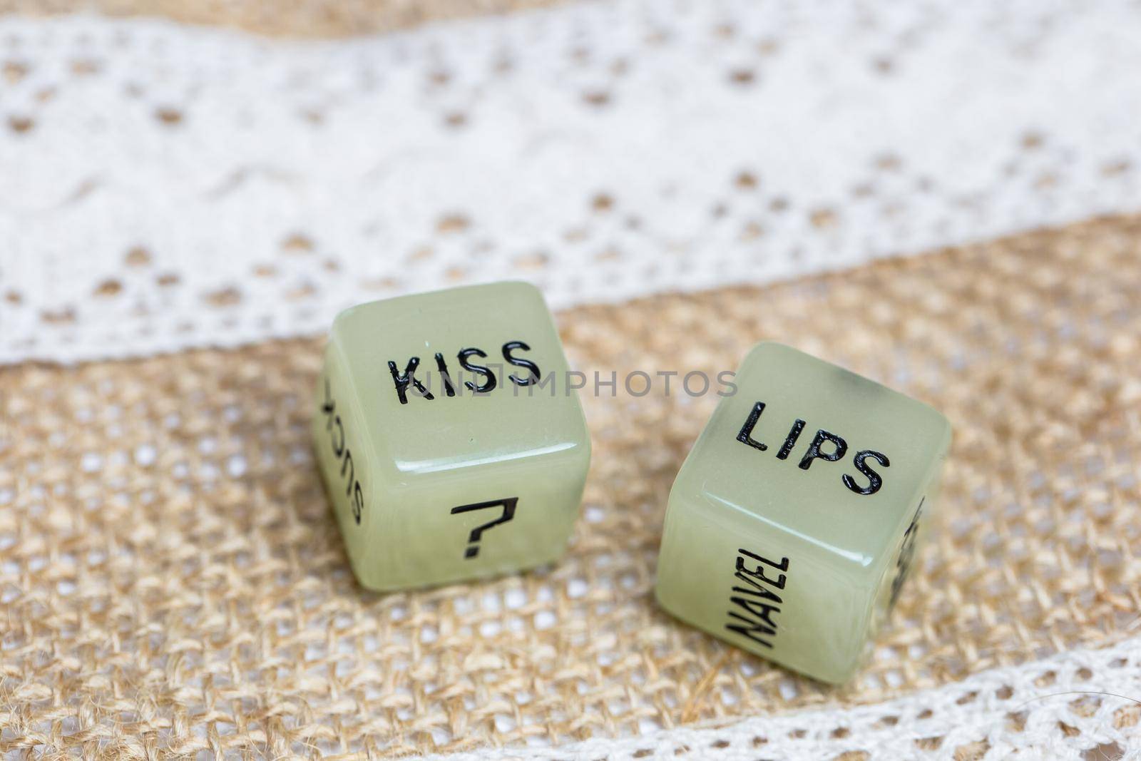 Two erotic dice for sexual game with cotton lace background texture, with the text Kiss lips for Valentines Day,sex,sensual,romantic, love concept close up