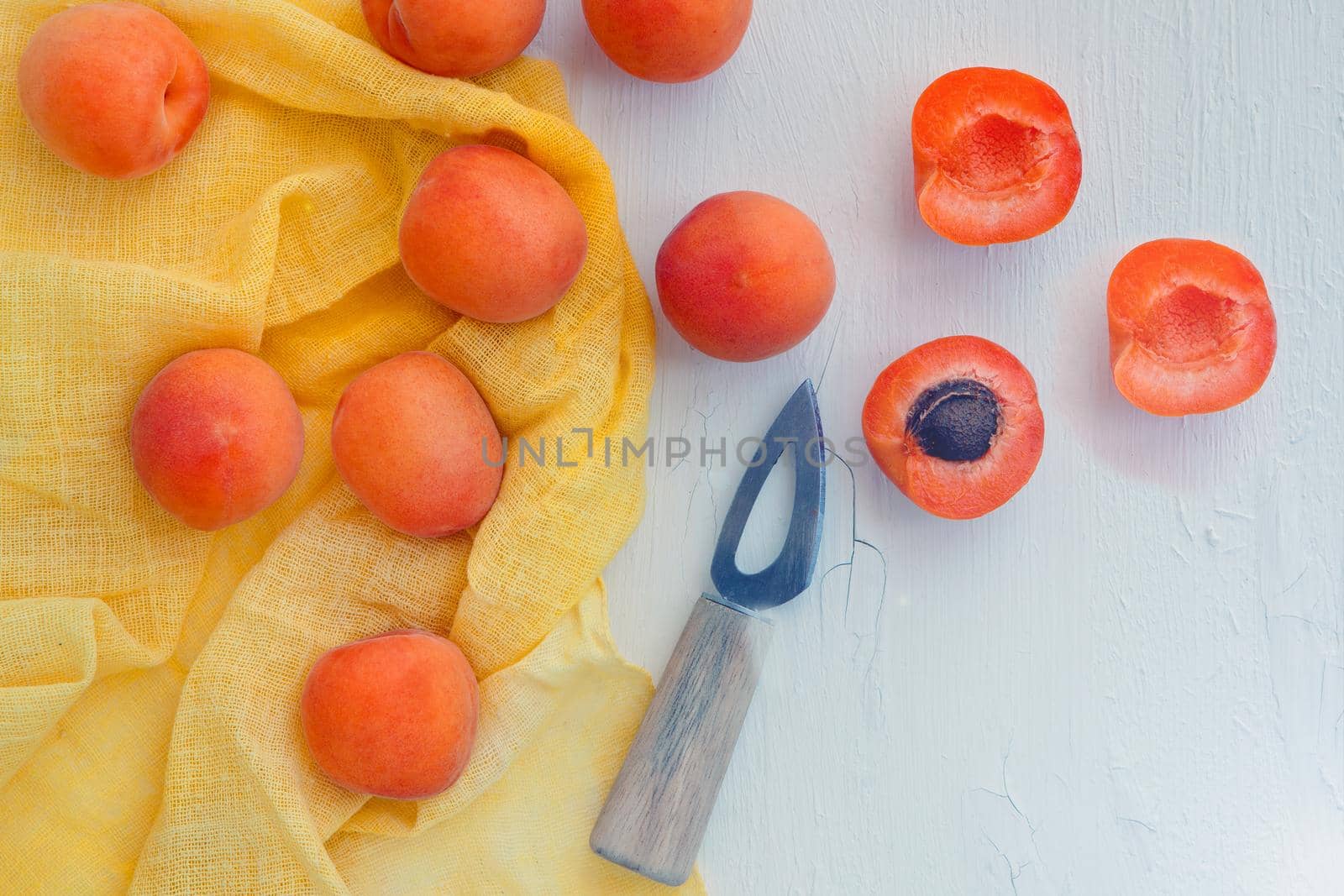 Delicious apricots with small knife on table close-up. Horizontal view from above with yellow napkin. space for text
