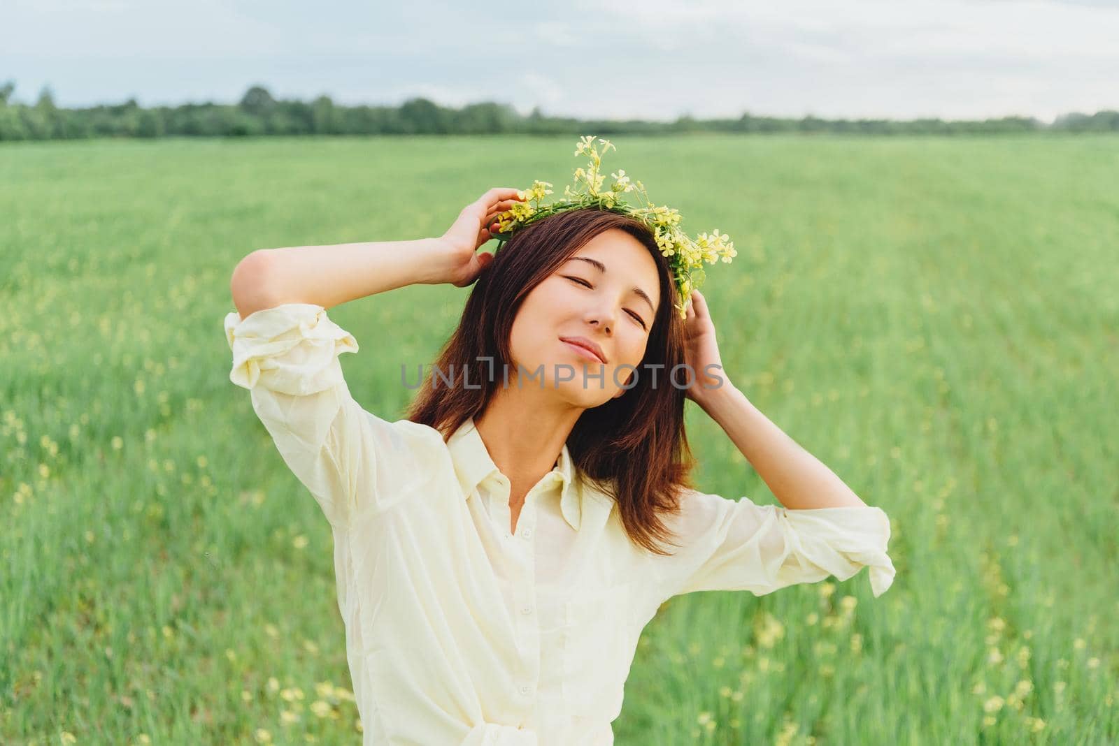 Smiling beautiful young woman with wreath of flowers enjoying a summer day