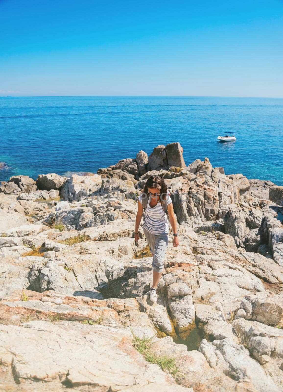 Young traveler woman walking on stone island in the sea