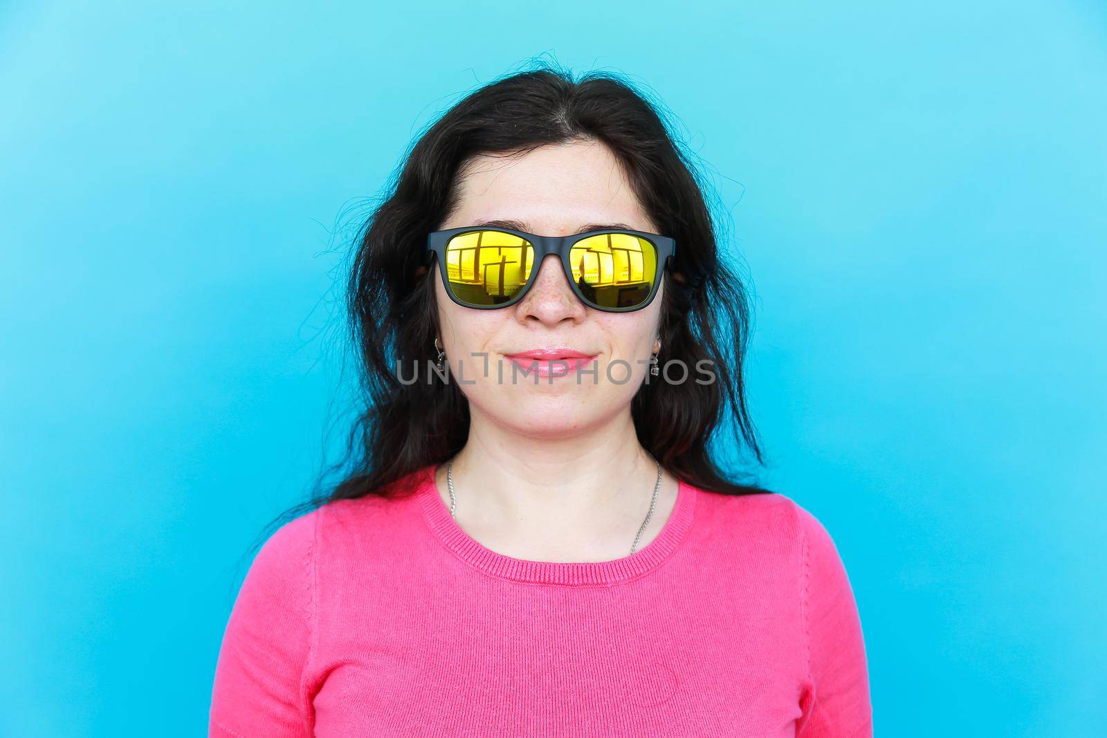 Fashion happy pretty smiling woman wearing a sunglasses over colorful blue background.