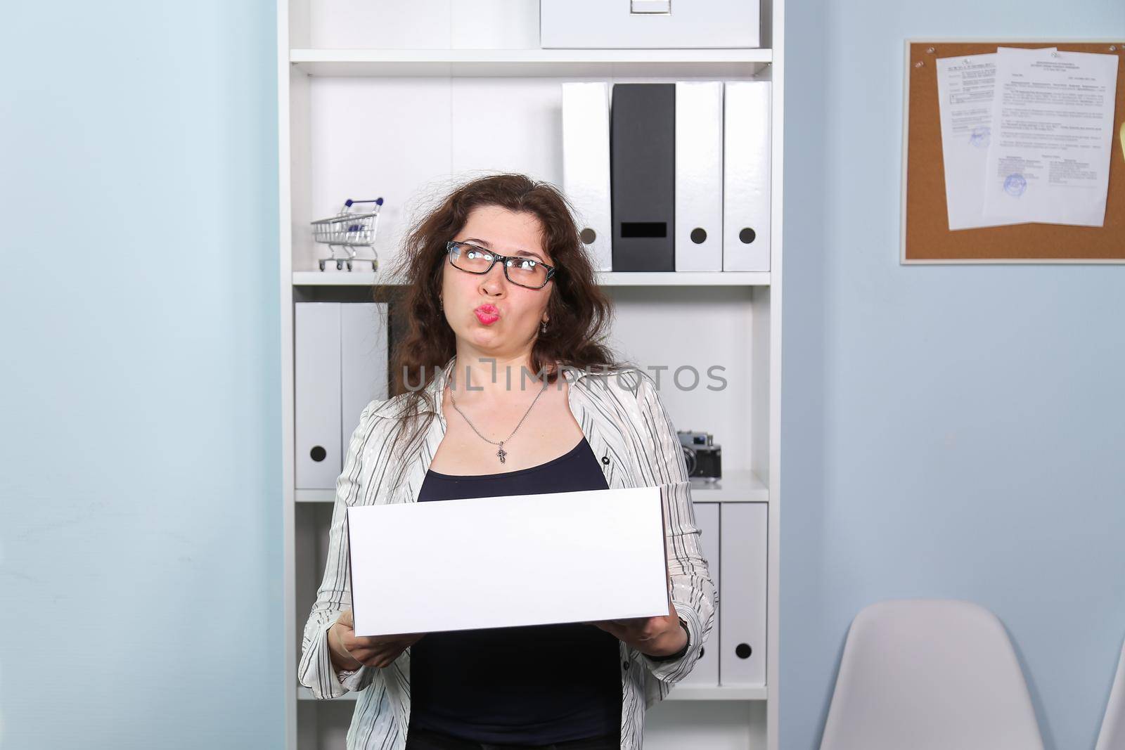 Concept of dismissal from work. Stunned woman with carton box with her stationery stuff, girl was fired from her job