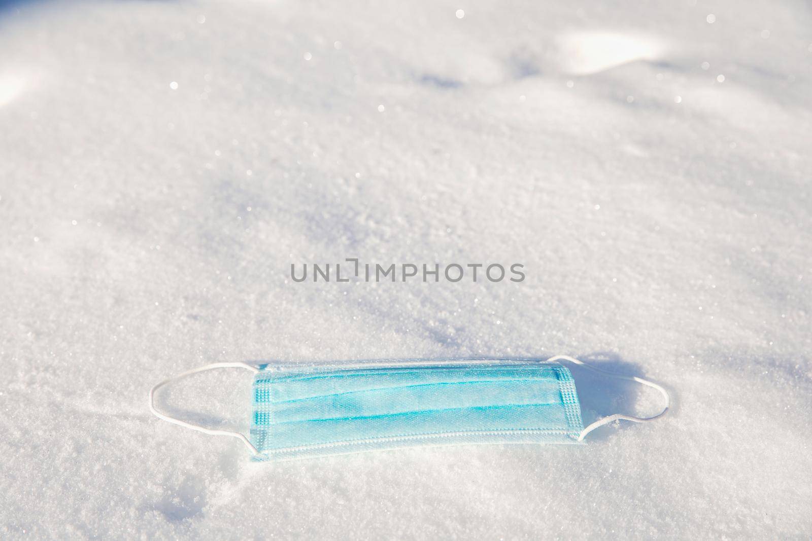 Protective blue medical mask for virus lies in the snow, Covid-19, pandemic,winter,virus,health concept, copy space background space for text