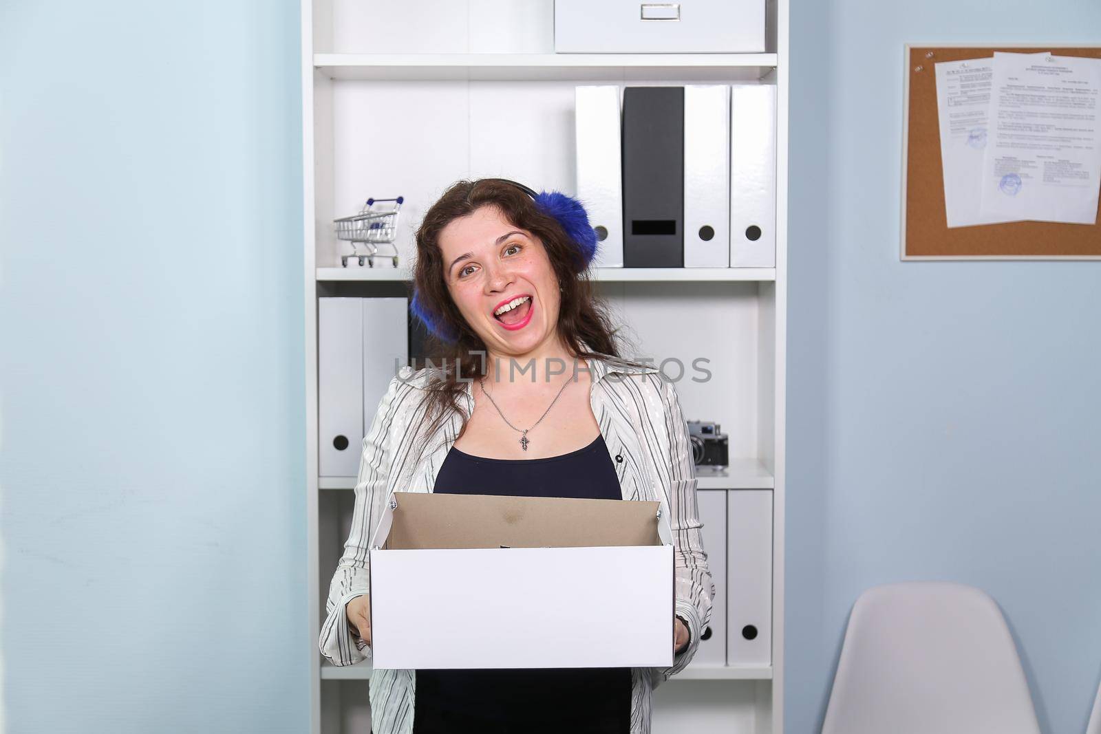 Concept of dismissal from work. Happy woman with carton box with her stationery stuff, girl was fired from her job