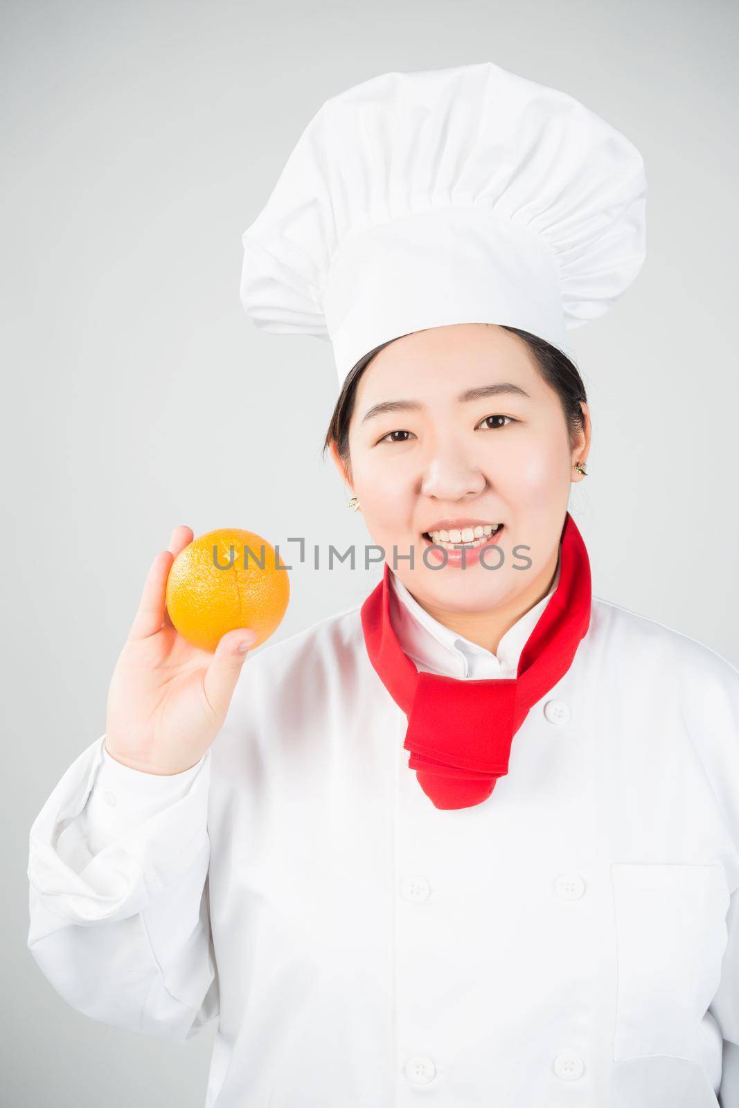 cooking and food concept - smiling female chef, holding orange