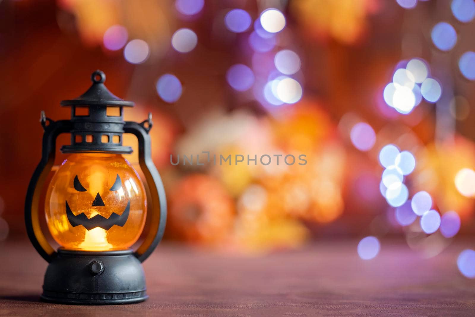 Jack o lanterns Halloween pumpkin face in lantern autumn colored background with bokeh lights and autumn leafs copy space