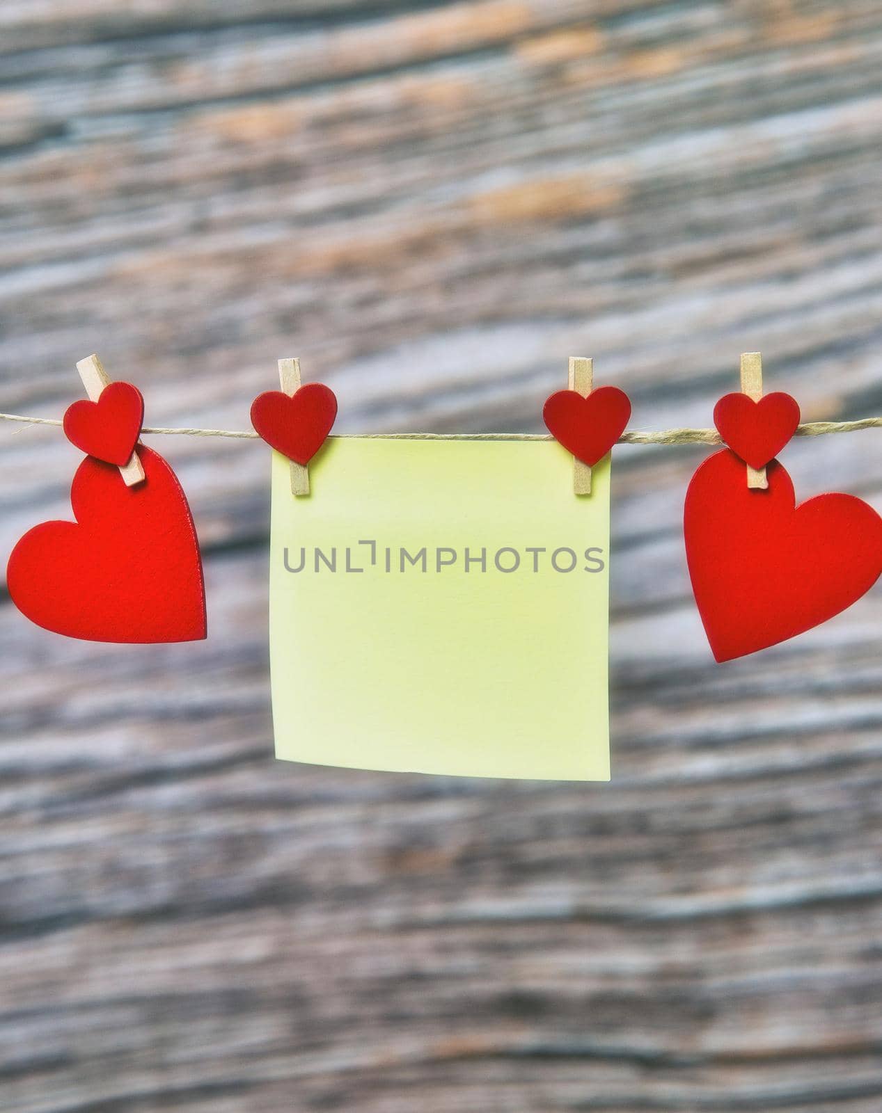 Blank sticky note with red hearts hanging against wooden background, Valentines Day, Womens Day Mothers Day concept, Copy space space for text
