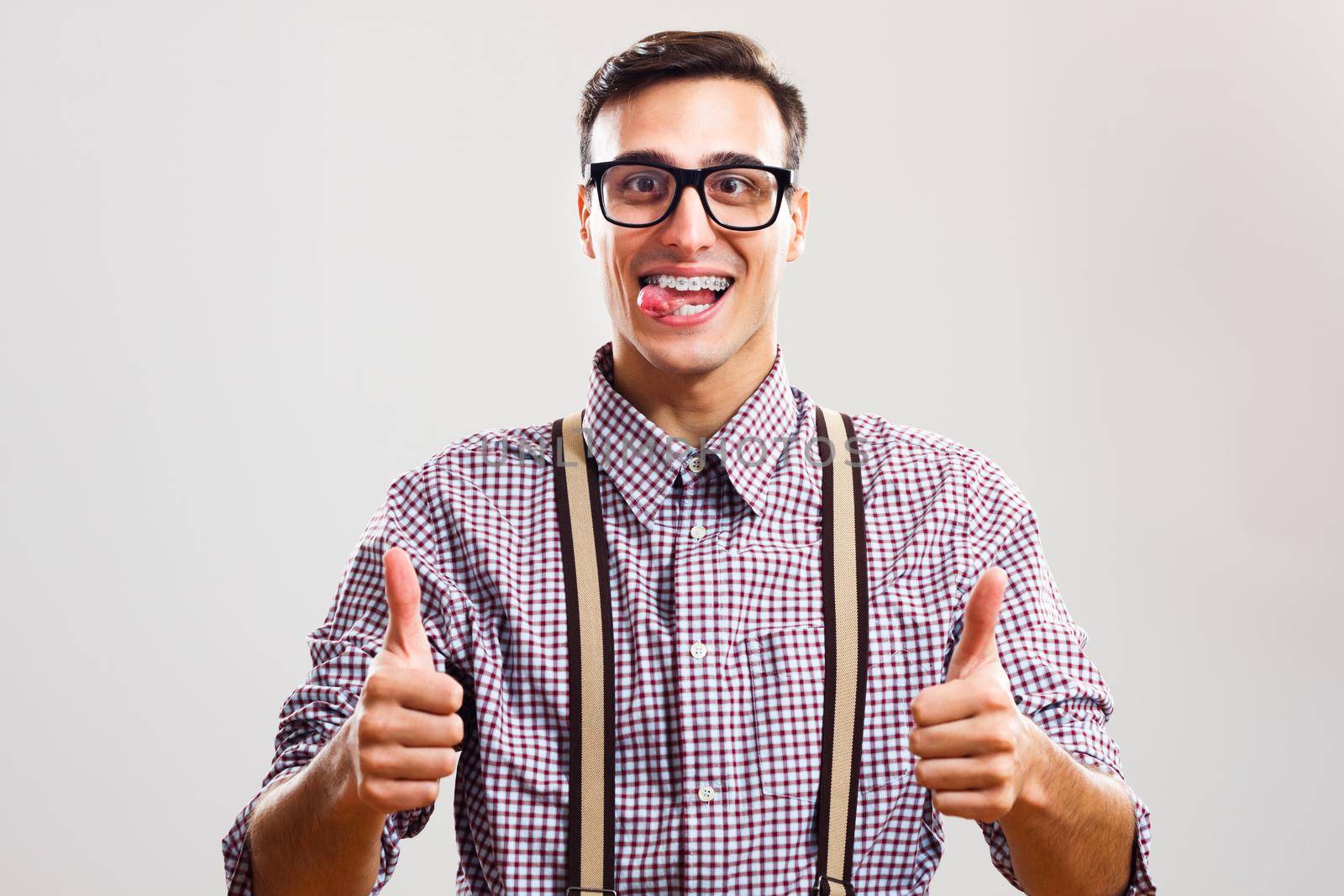 Portrait of nerdy man giving thumb up and sticking out tongue