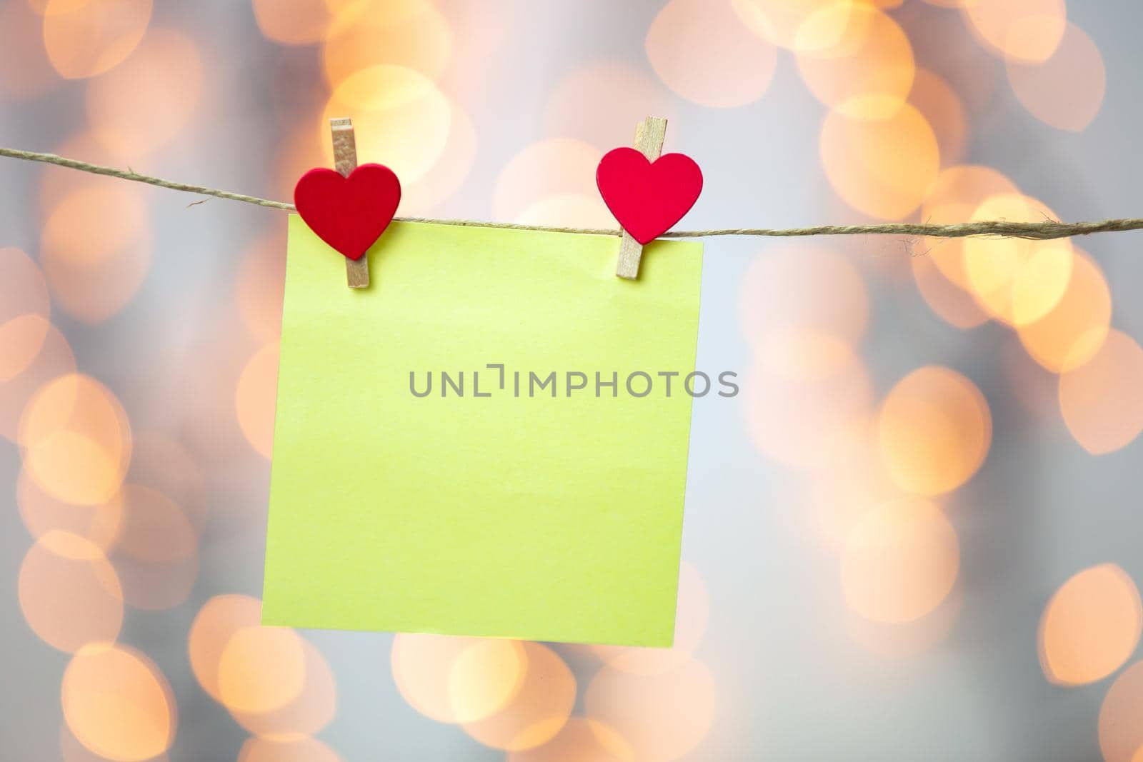 Blank Yellow sticky note hanging with red hearts with bokeh background, romantic Valentines day concept background copy space love