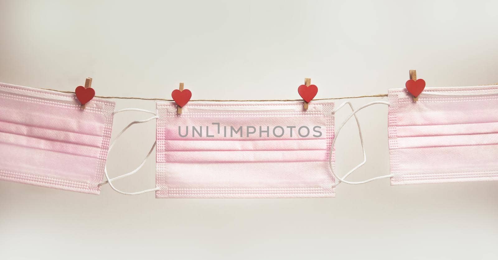 Pink protective medical mask hanging with clothes pegs in heart shape isolated on white background, Health, Covid-19 or Valentine's Day concept background love