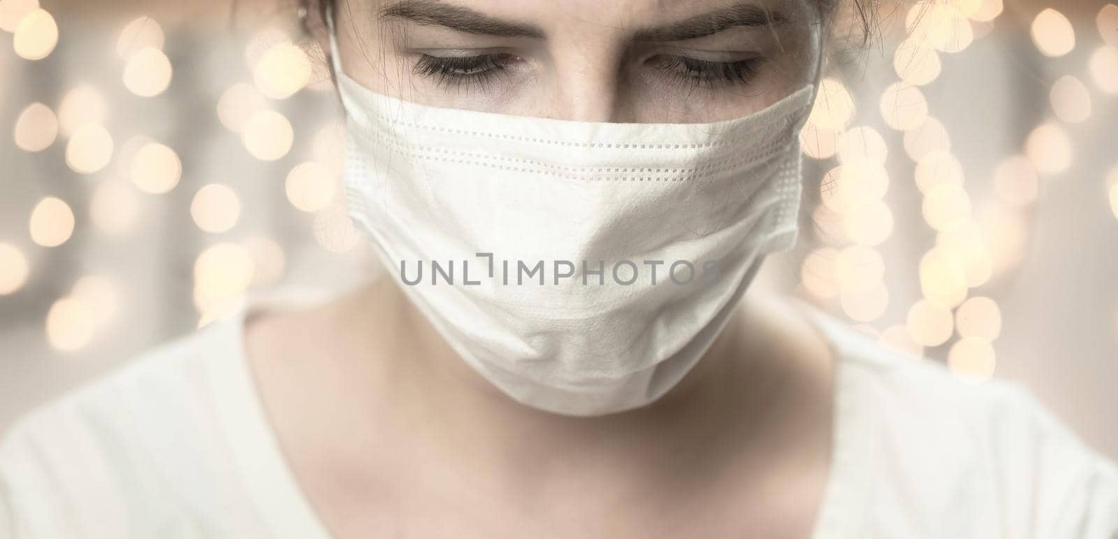 Young female wearing protection face mask against coronavirus looking down bokeh background. medical staff preventive gear. Covid-19 and Health concept background bokeh background