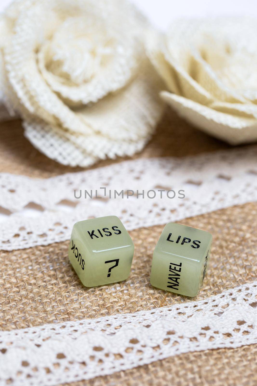 Two erotic dice for sexual game with cotton lace background texture, with the text Kiss lips for Valentines Day,sex,sensual,romantic, love concept close up