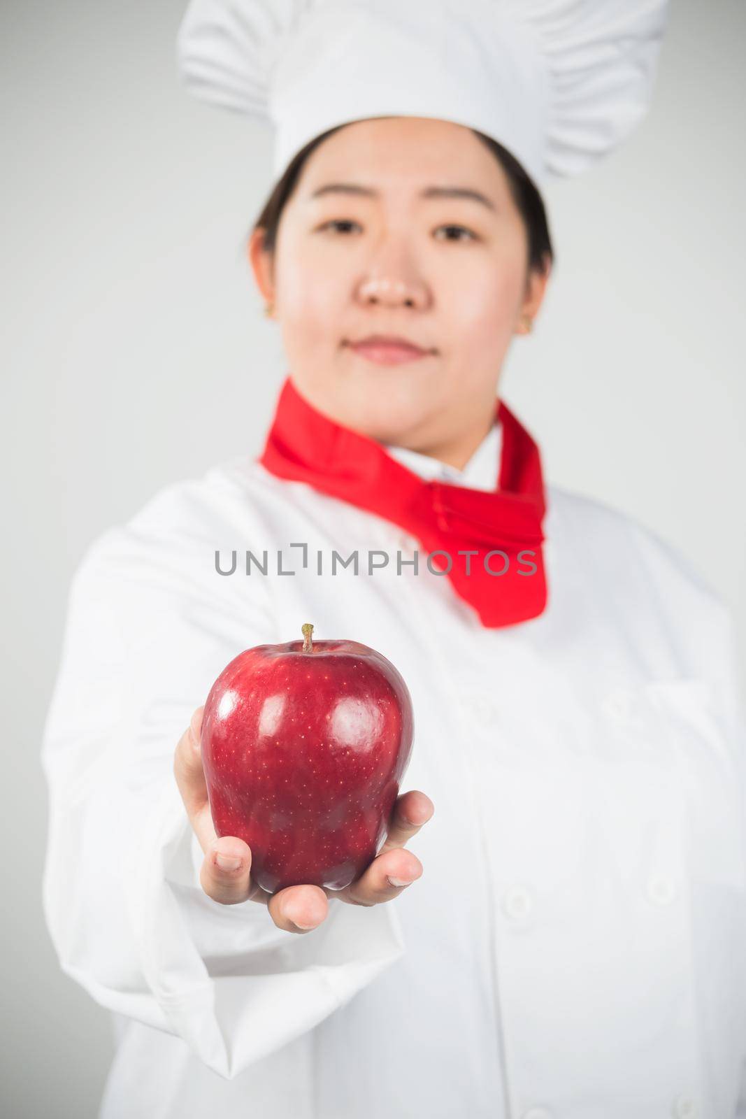 cooking and food concept - smiling female chef, holding a Red Delicious