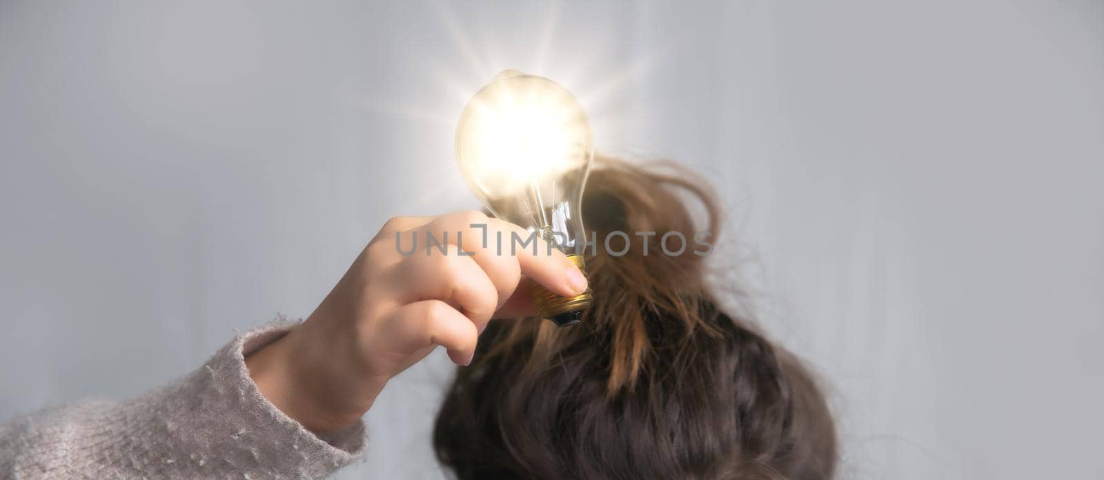Young female holding light bulb above head in her hand,creativity,business,solution,thinking,ideas concept, copy space space for text