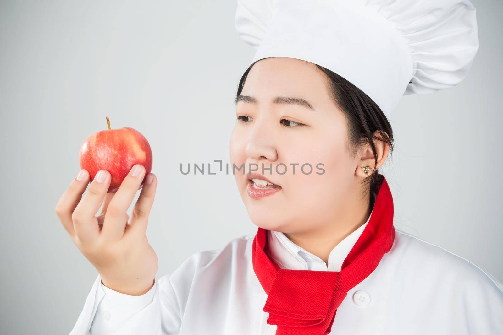 cooking and food concept - smiling female chef, holding a red apple