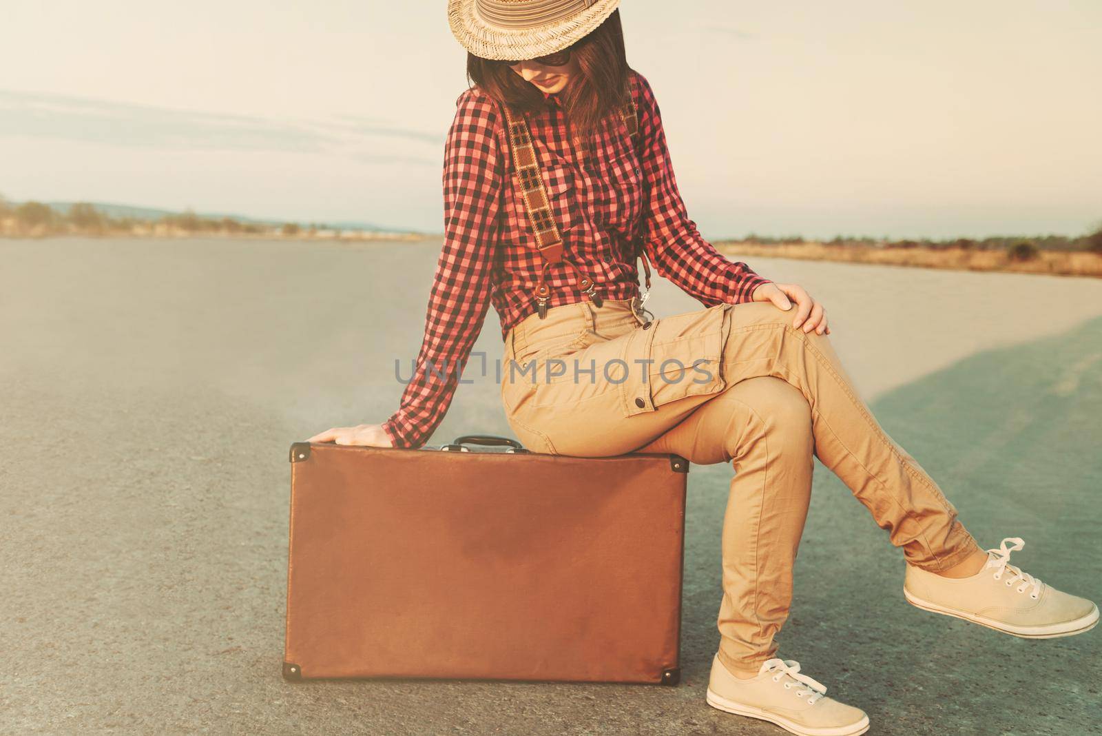 Traveler young woman sitting on suitcase. Low contrast effect