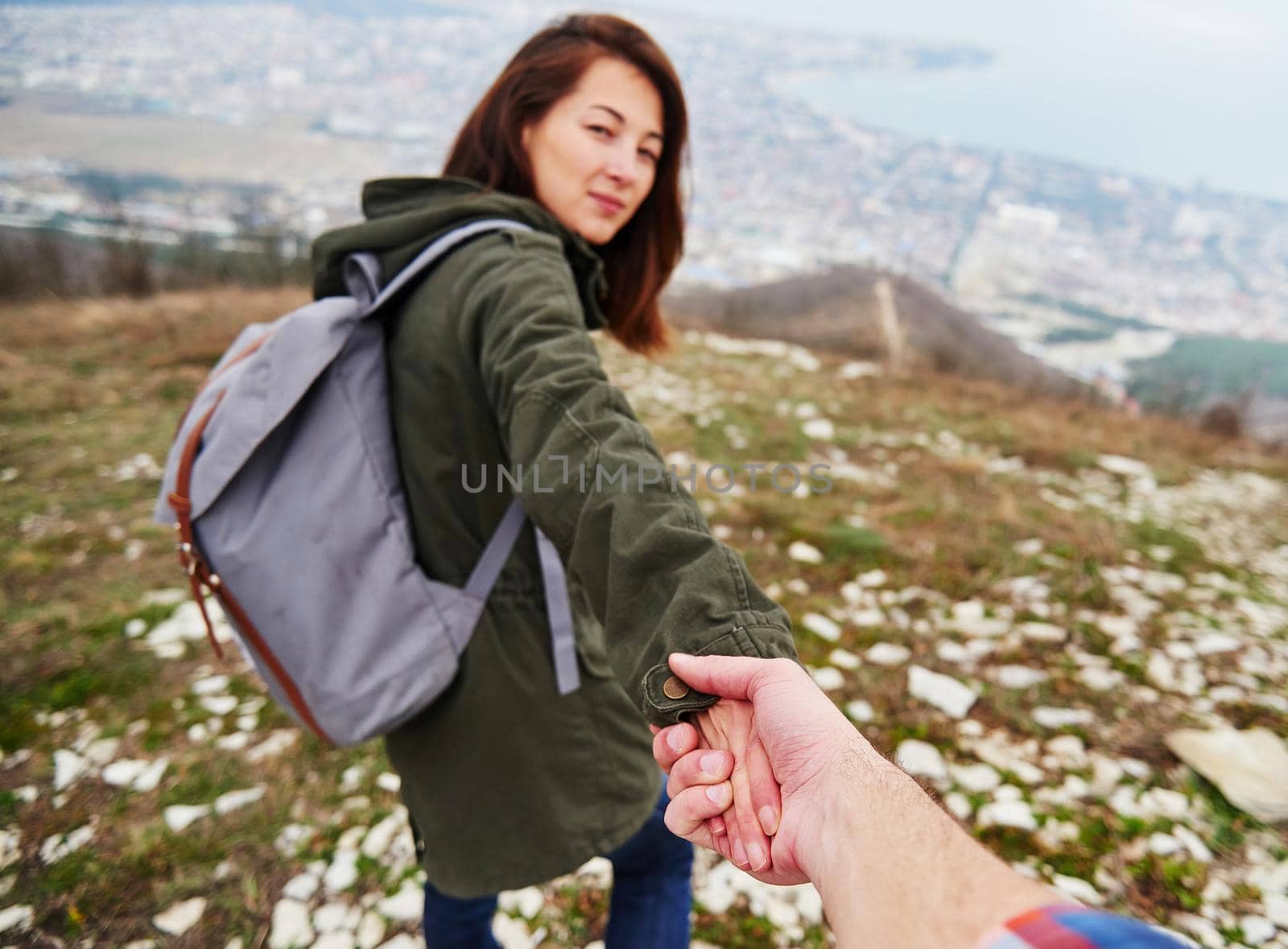 Young traveler woman holding man's hand and leading him on nature. Couple in love. Focus on hands