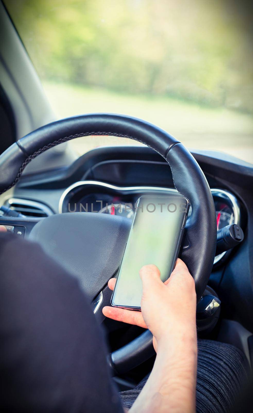 Young man driver using mobile phone in car, hand holding smart phone and driving and texting, transport business concept by Annebel146
