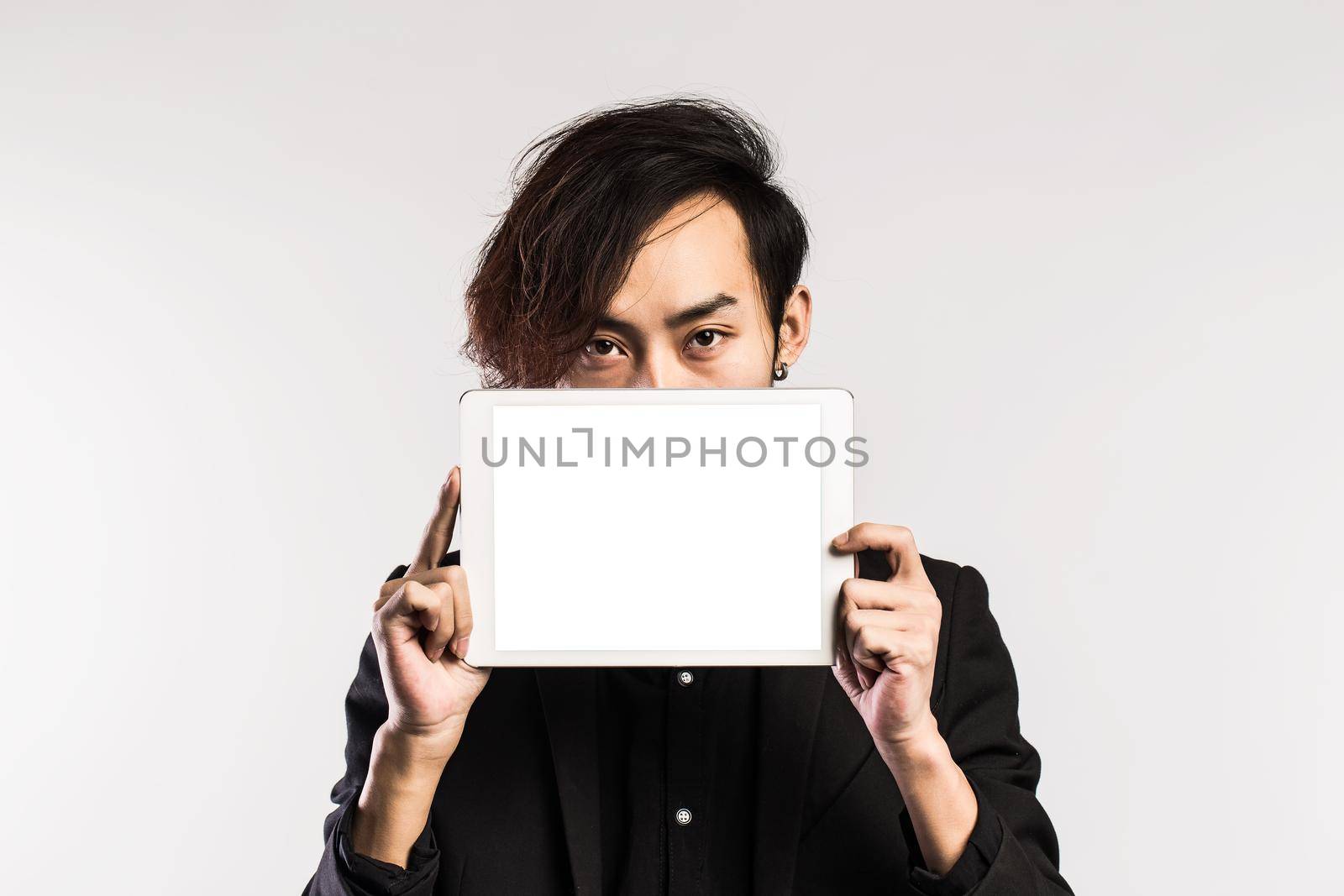 Serious young male executive using digital tablet against gray background by whatwolf