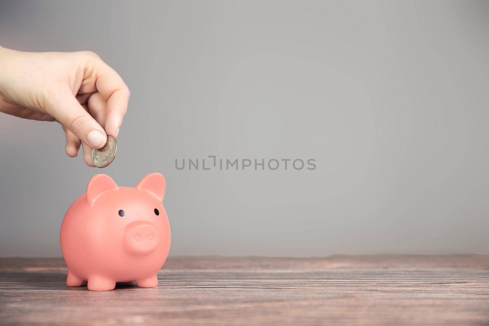 Human Hand Putting Coin In pink Piggy Bank on blurred background, Saving, business,financial concept copy space retro modern design