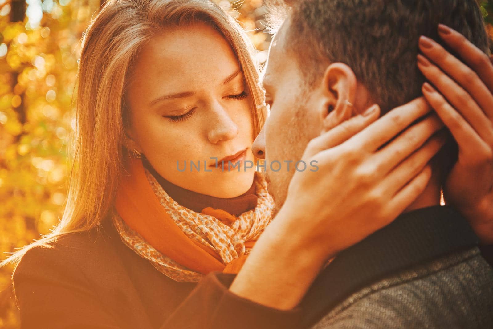 Young beautiful woman with closed eyes embraces a man in autumn park, tenderness scene