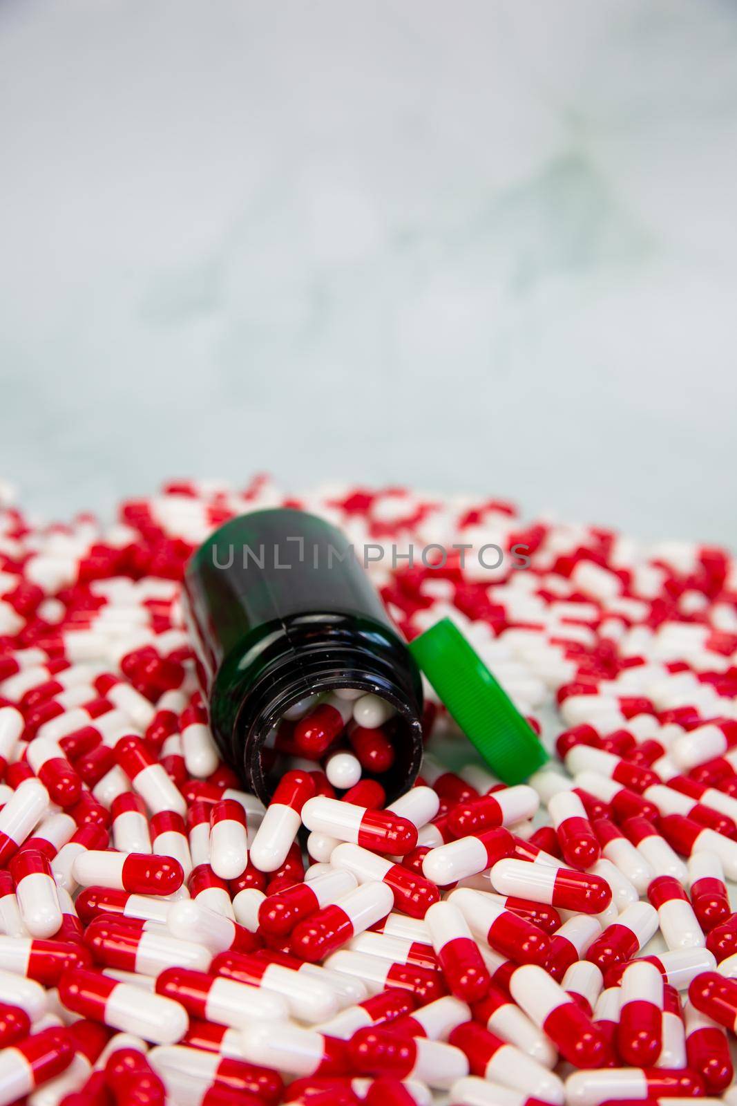 Bottle with red and white capsule on white background, Vitamin,drugs or pharmaceutical medication background, Health, medical and business concept by Annebel146