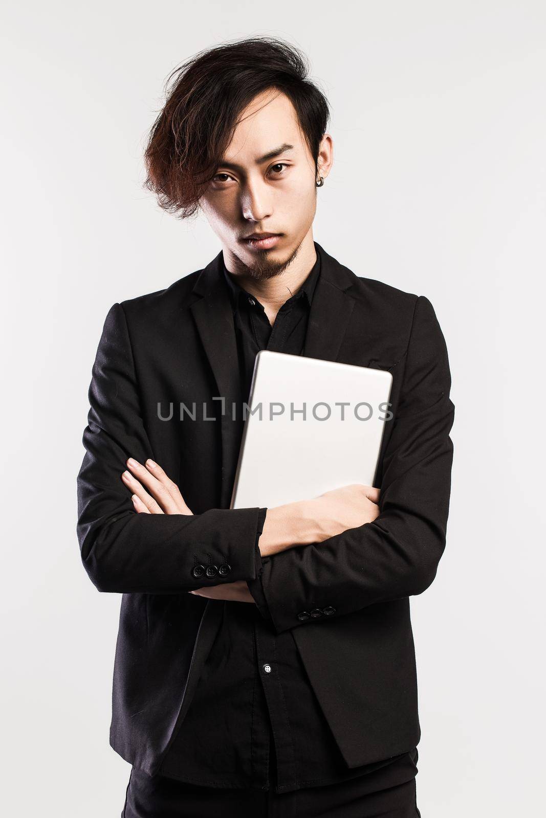 Serious young male executive using digital tablet against gray background