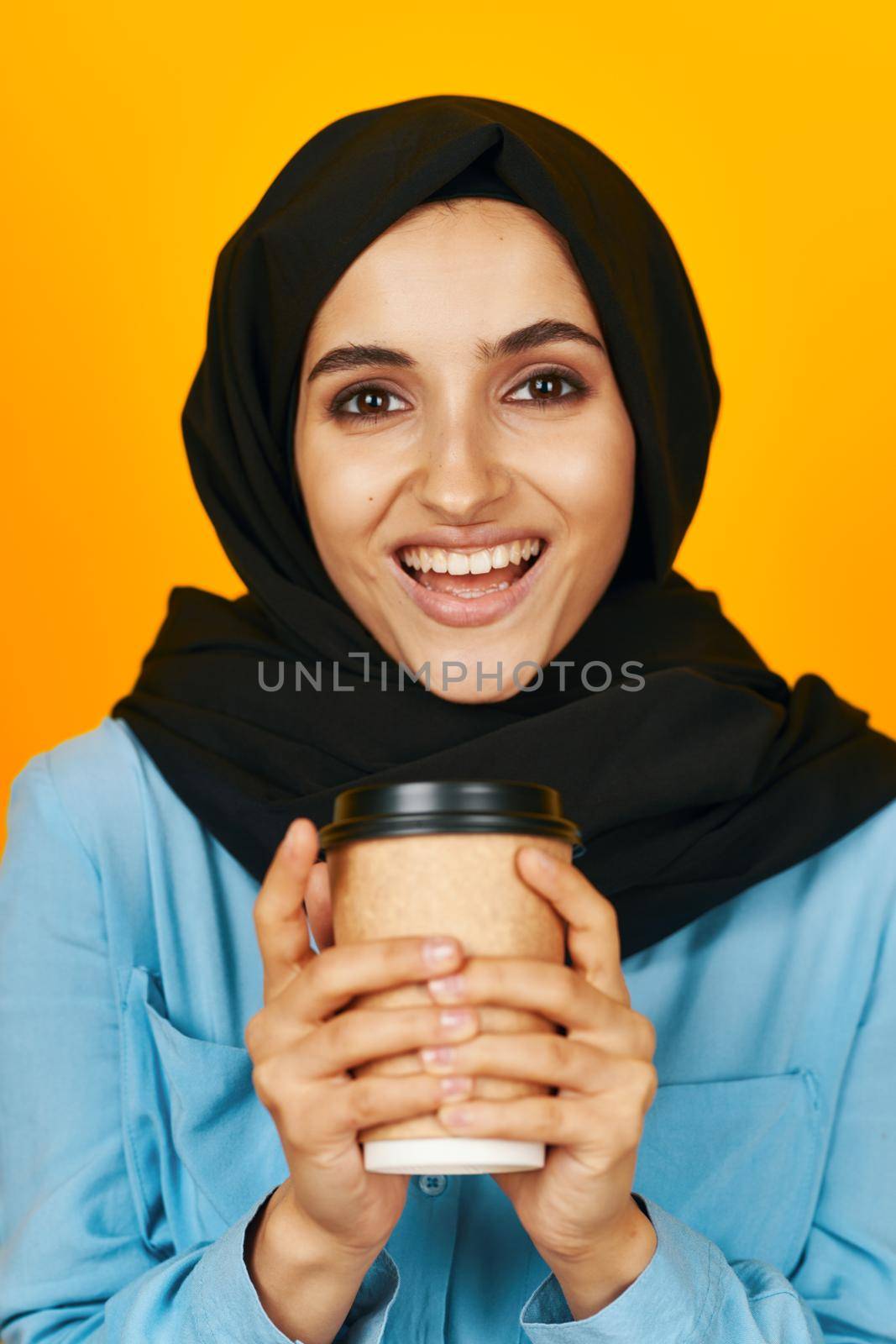 woman in black hijab glass with a drink emotion relaxation yellow background by Vichizh