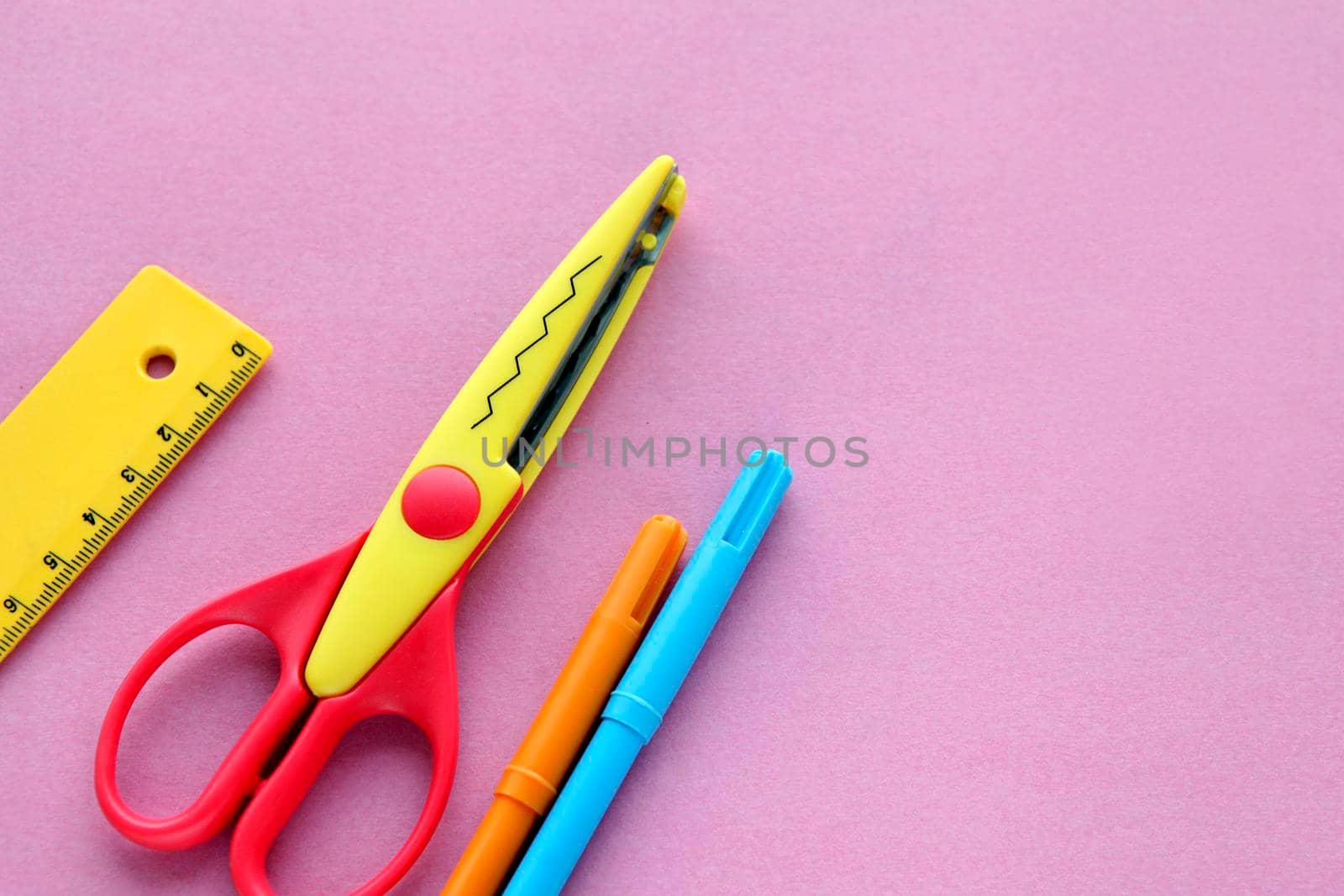 scissors, ruler and crayons on a pink background. Creative, fashionable, minimalistic, school or office workspace with supplies on cyan background. Flat lay.