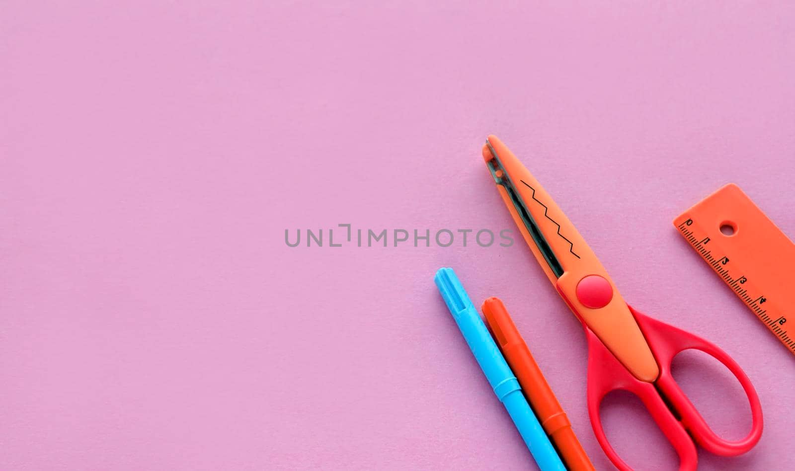 scissors, ruler and crayons on a pink background. Creative, fashionable, minimalistic, school or office workspace with supplies on cyan background. Flat lay.