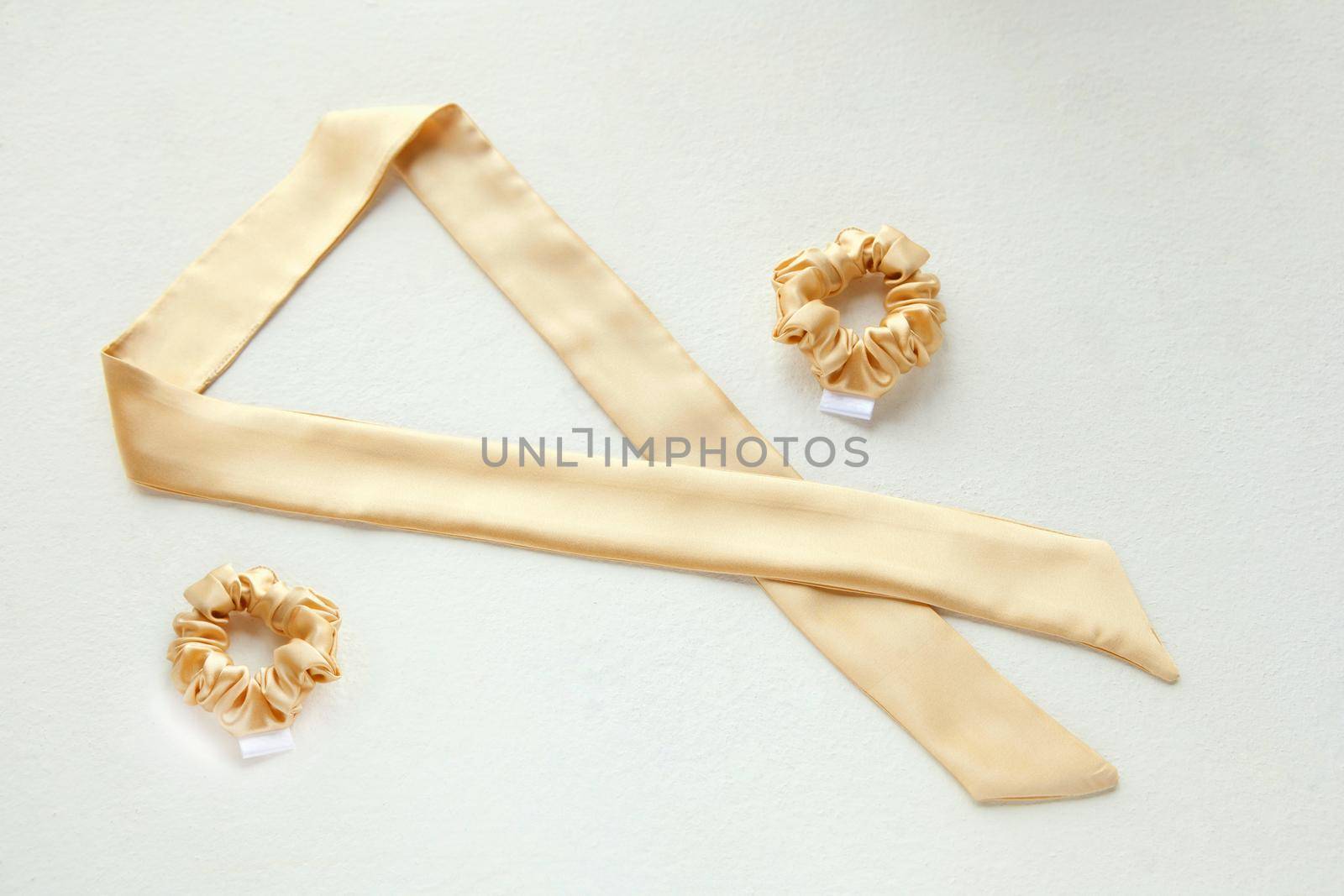 golden silk scrunchy flat lay on white. Hairdressing tools and accessories. luxury ladyes Hair Scrunchie, Elastic Hair Band, Bobble Sport Scrunchie Hairband. hair scarf fixed on the scrunchie