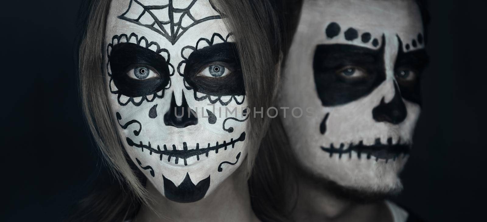 Loving young couple with sugar skull makeup. Halloween face art
