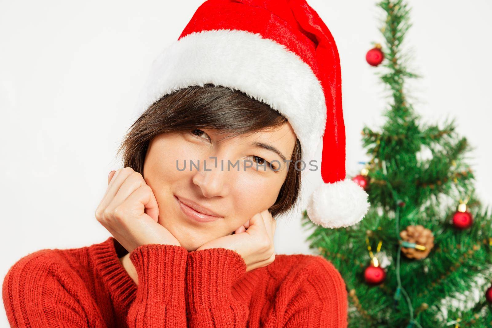 Portrait of a beautiful woman in a santa hat on a background of Christmas tree