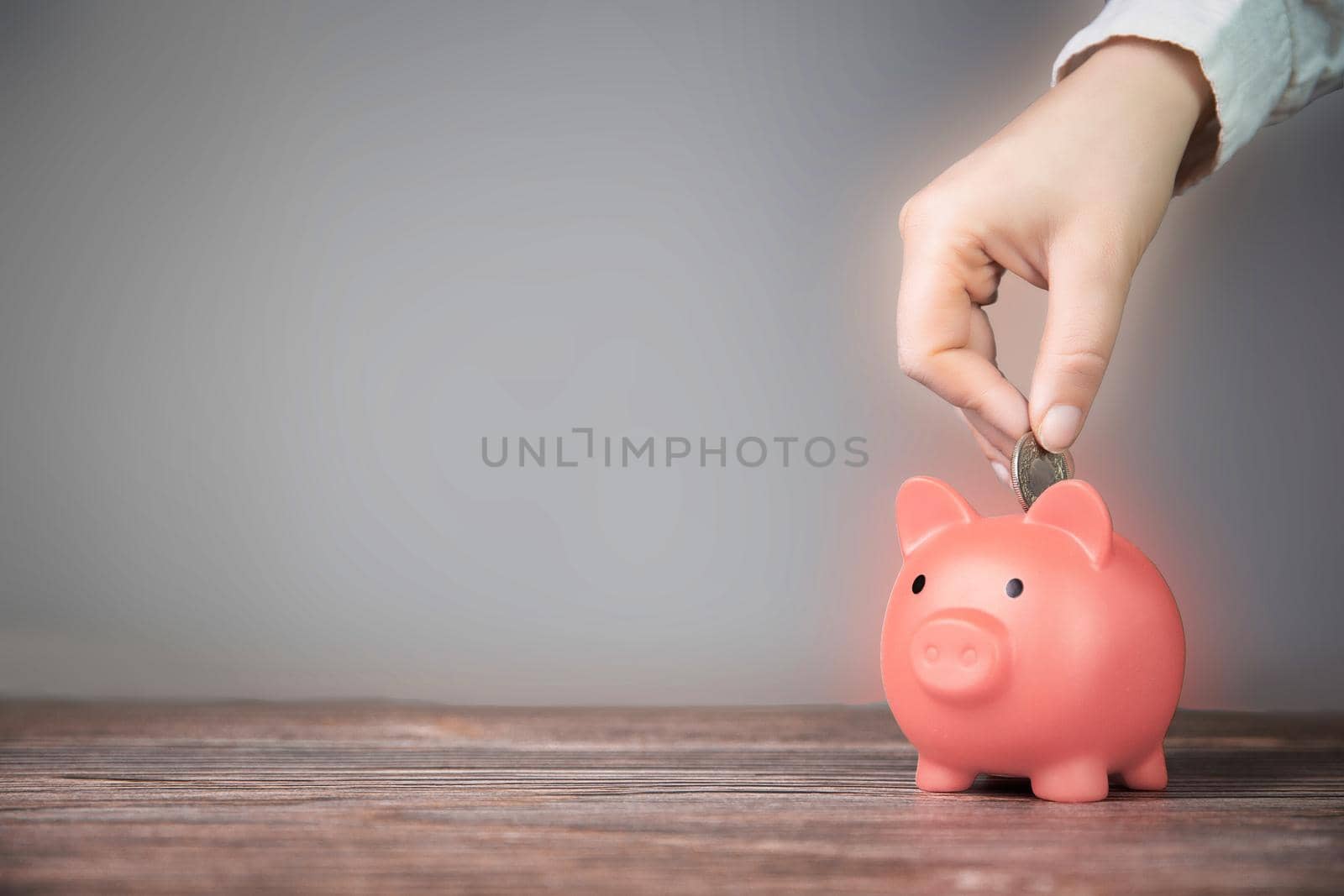 Human Hand Putting Coin In pink Piggy Bank on blurred background, Saving, business,financial concept copy space retro modern design