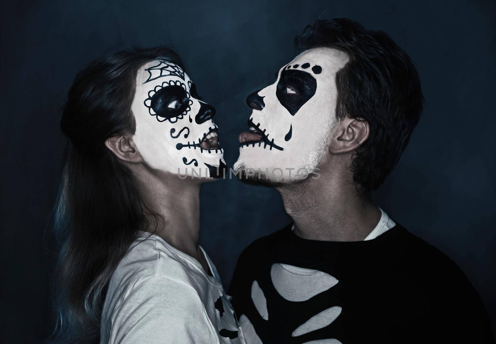 Funny Halloween loving couple in costumes of skeletons and sugar skull makeup