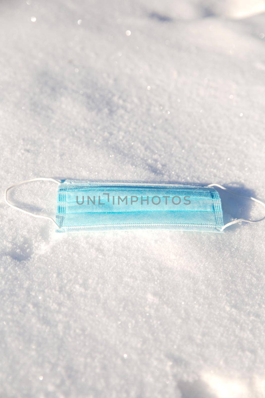 Protective blue medical mask for virus lies in the snow, Covid-19, pandemic,winter,virus,health concept, copy space background space for text