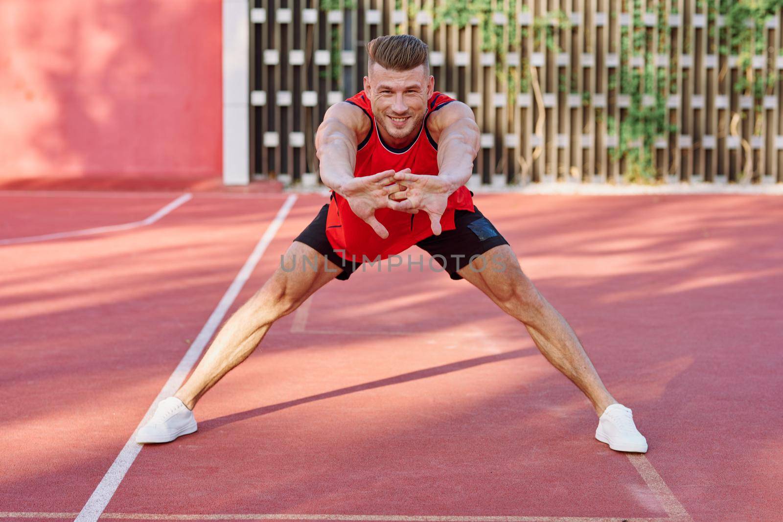 athletic man in red jersey on the sports ground exercise by Vichizh