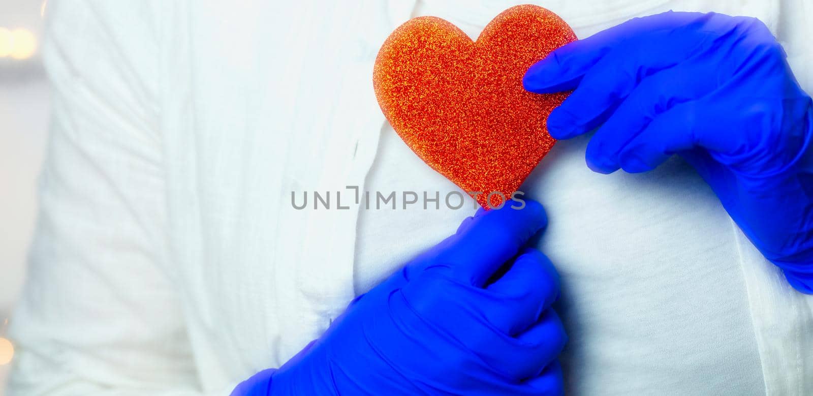 Healthcare worker holding red heart with blue medical gloves for epidemic coronavirus or other virus, health and love Valentine concept. human beauty