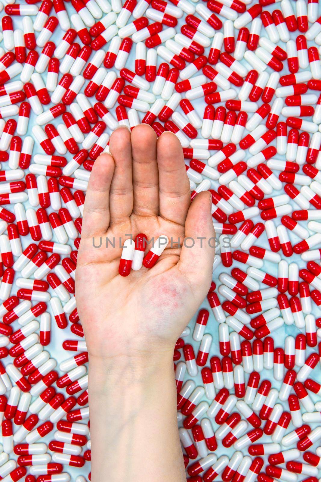 hands holding red and white capsules for medication, vitamin or drugs background on white background. Top view. Flat lay. Copy space. Close up. Medicine,business and health concept colorful