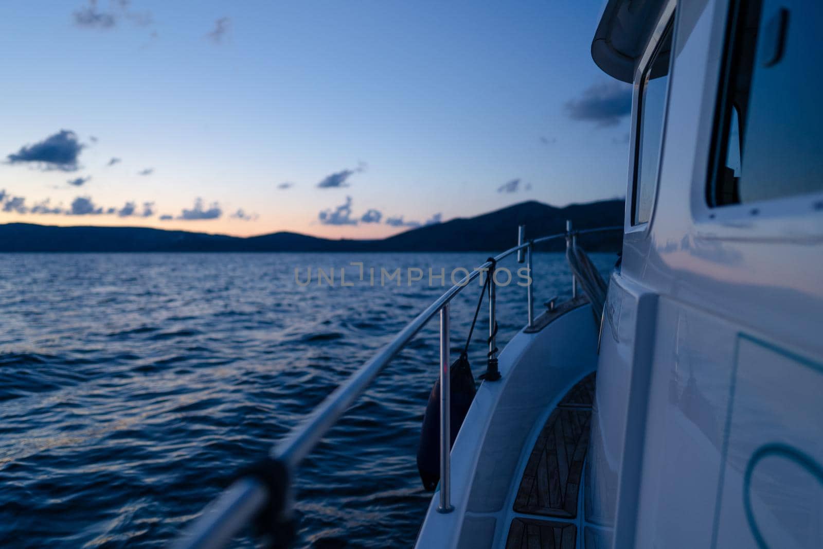 Deck of white yacht sailing in open sea at sunset, close up