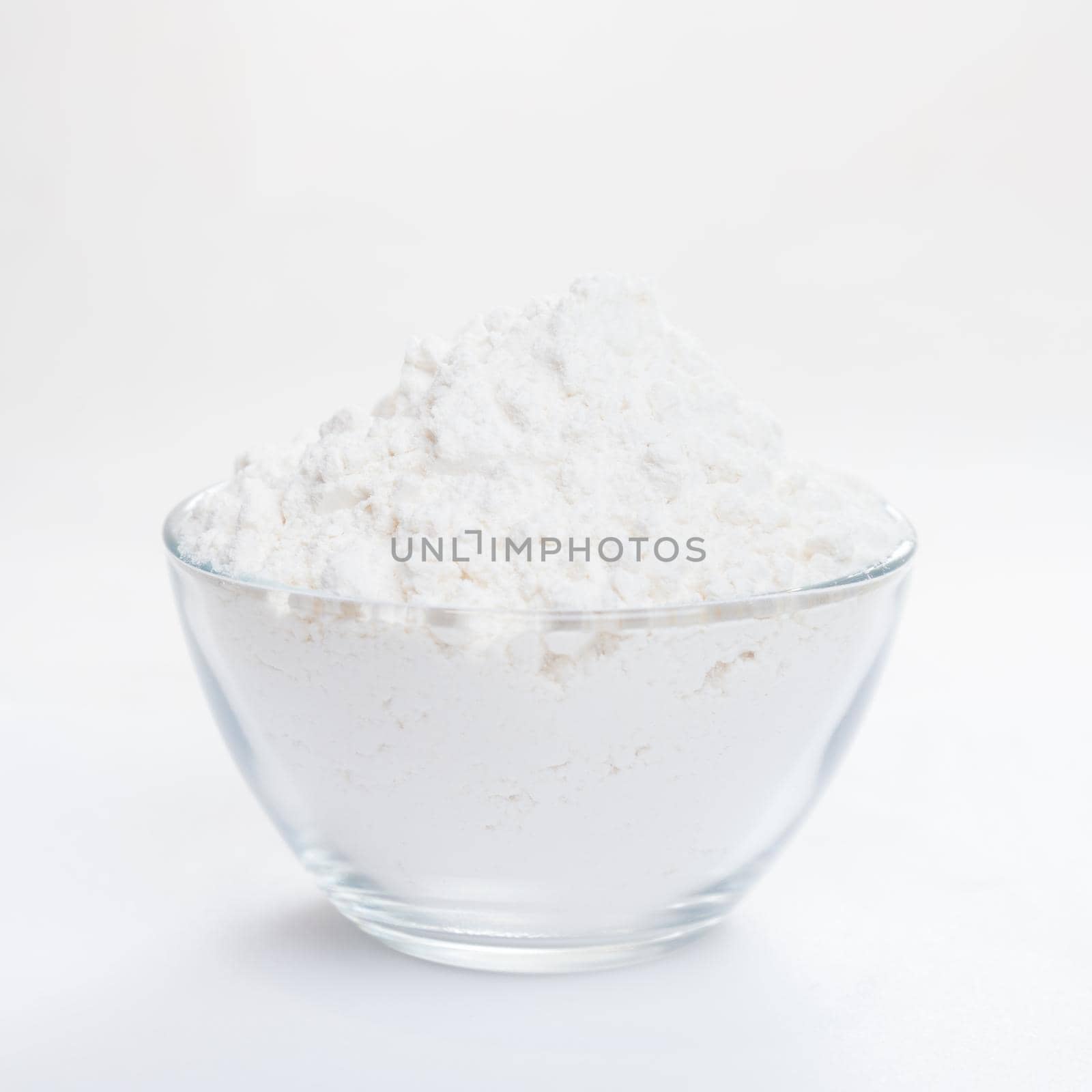 White flour in a transparent bowl, side view